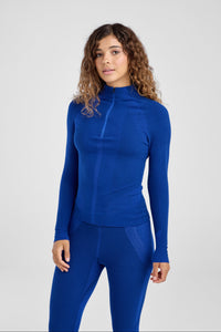 Woman wearing a blue baselayer outfit on a light gray background