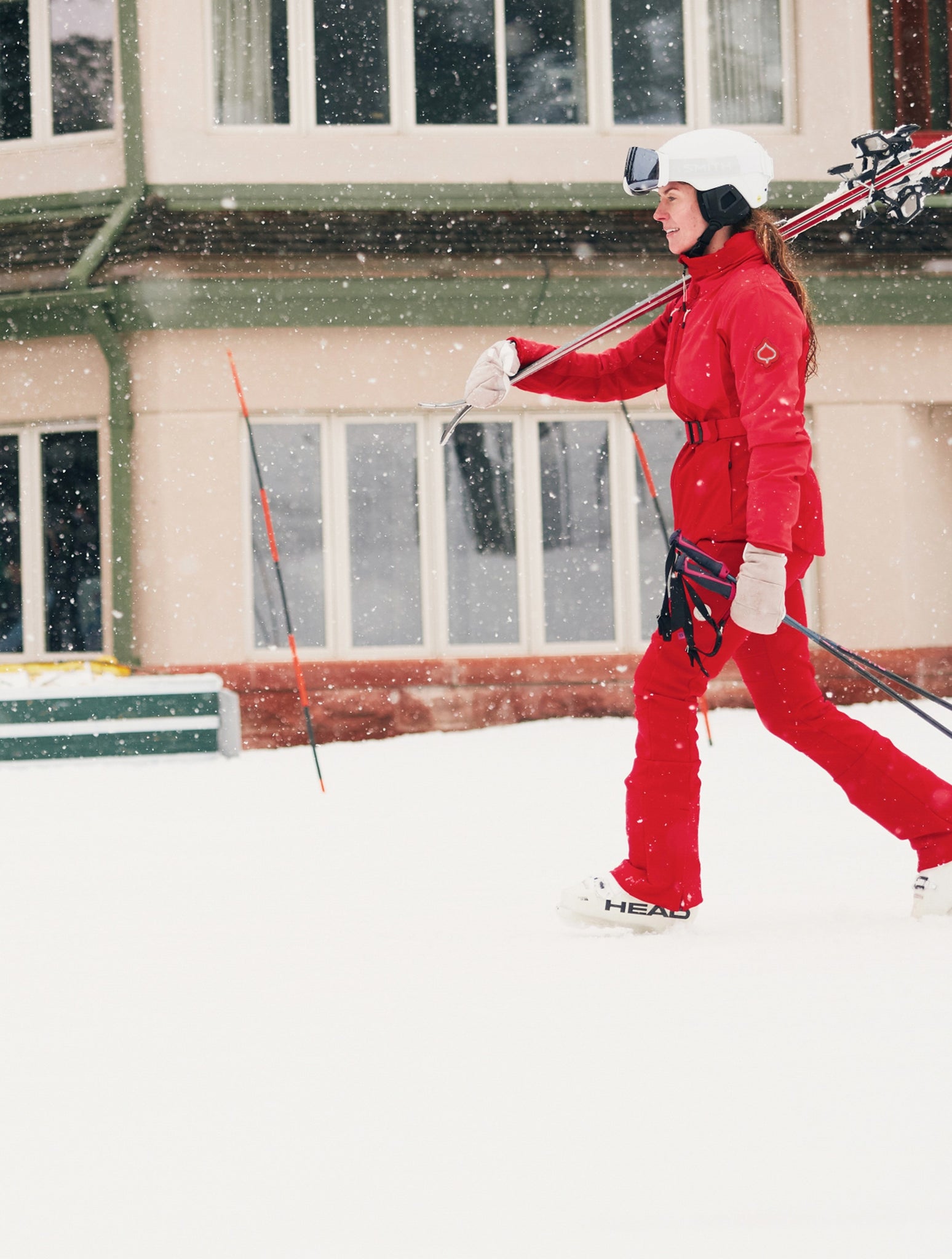 Person in red ski suit with skis and poles on a snowy day.