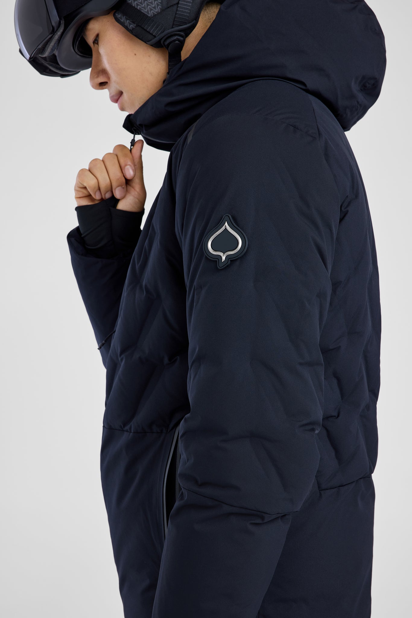 Person wearing a black winter jacket with a brand logo on a white background