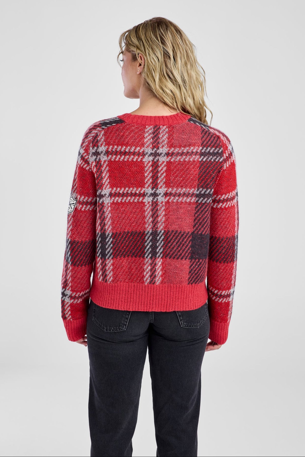Person wearing a red plaid sweater on a plain background