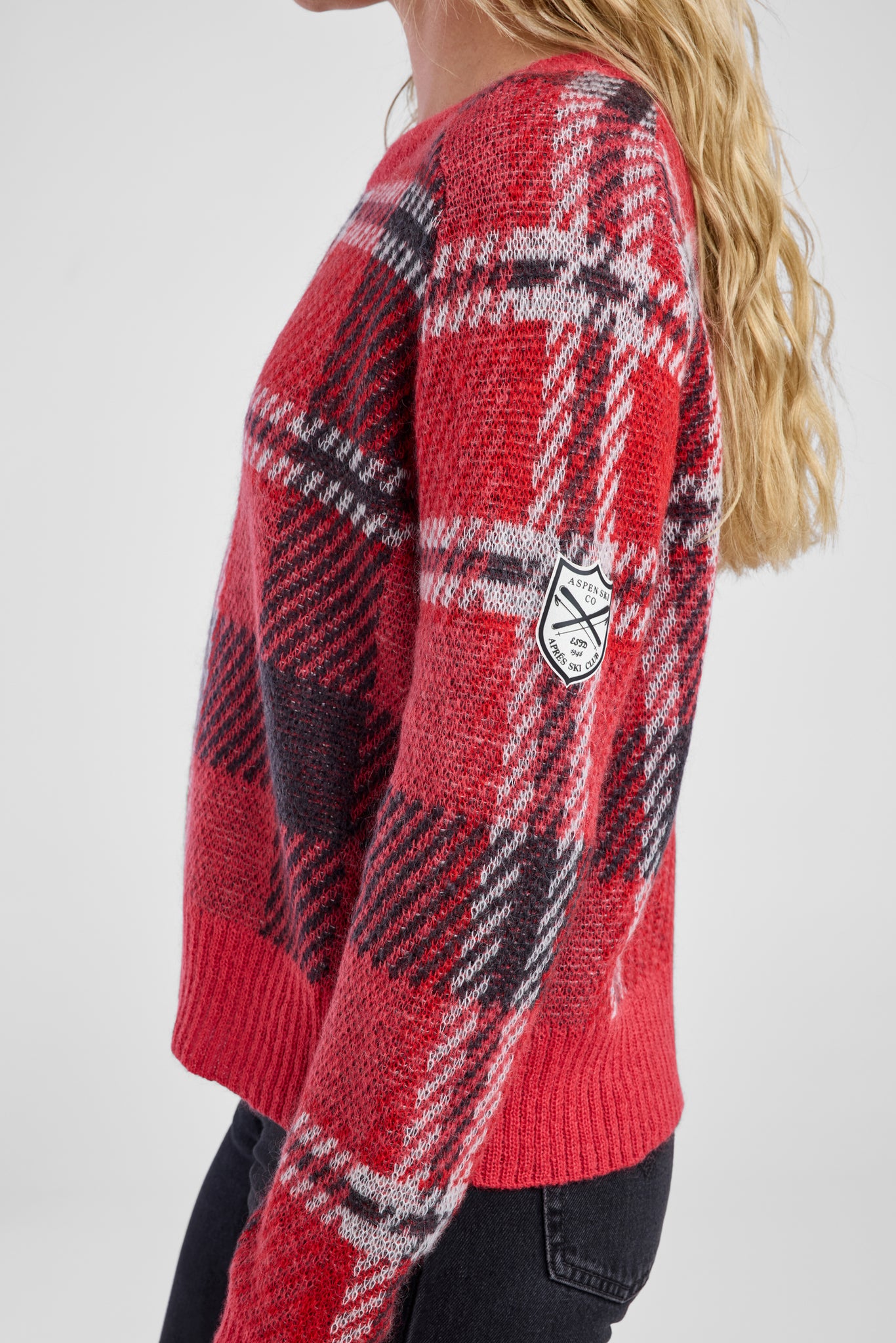 Side view of a woman wearing a red plaid sweater with white detail patch
