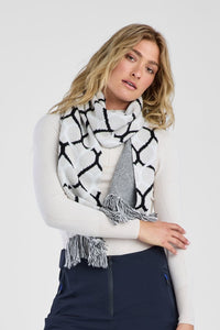 Woman wearing navy pants, a white sweater with black patterns, and a patterned scarf on a white background